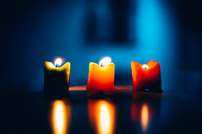 Close-up of three candles burning indoors