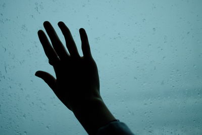 Close-up of hand touching wet window