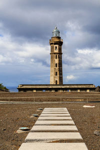 View of lighthouse by building against sky