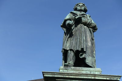 Low angle view of statue against blue sky