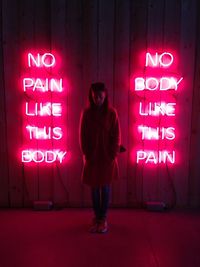 Full length of man standing against illuminated wall