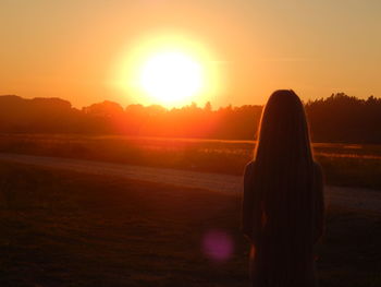 Rear view of silhouette woman standing on beach at sunset