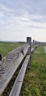 Wooden fence on field against sky