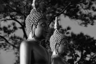 Close-up of buddha statue against trees