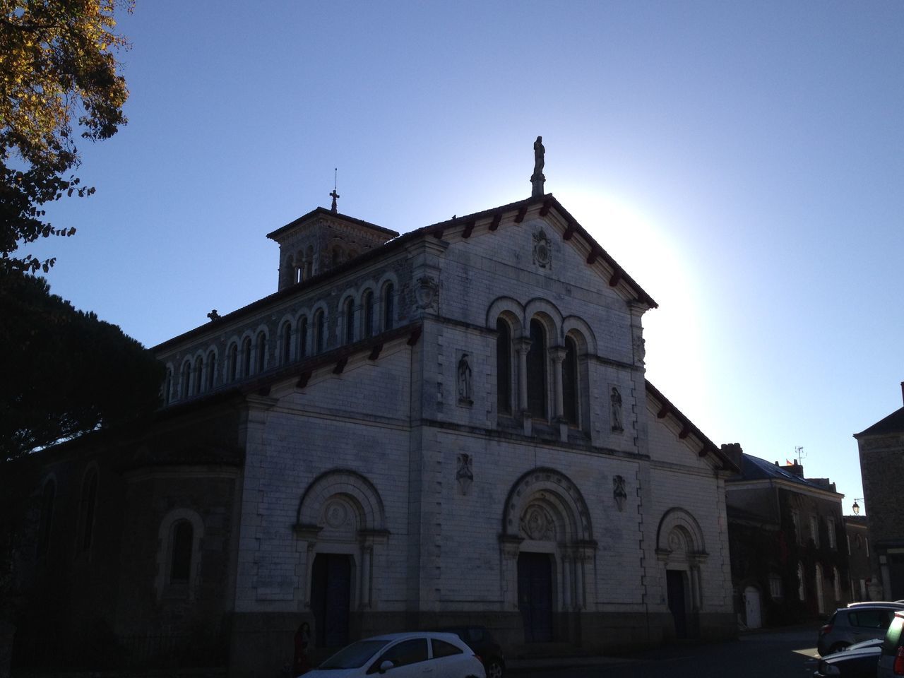 architecture, building exterior, built structure, clear sky, church, religion, place of worship, low angle view, spirituality, blue, arch, copy space, sunlight, facade, cross, sky, outdoors, history