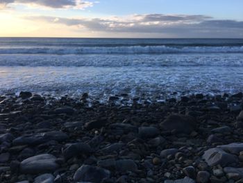 Close-up of pebbles on beach against sky during sunset