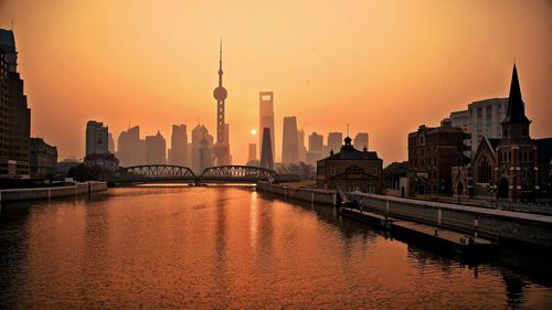 River with buildings against clear sky at sunset