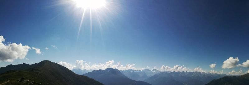 Panoramic view of mountains against blue sky on sunny day