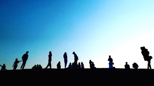 Low angle view of silhouette people against blue sky