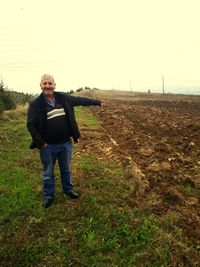 Full length portrait of man standing on field against sky