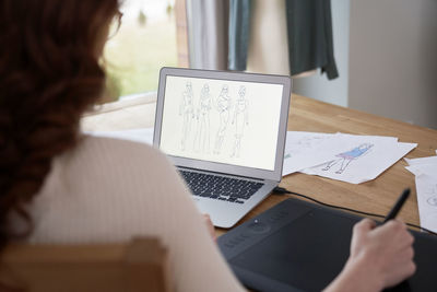 Midsection of woman using laptop on table