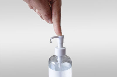 Close-up of hand holding bottle against white background