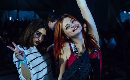 Young woman with arms raised in background at night