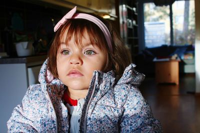 Close-up of cute girl looking away at home