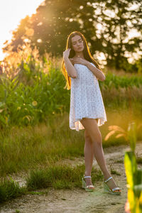 Young beautiful woman in white dress in corn field.