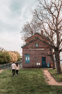 Couple outside house against sky