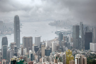 Aerial view of buildings in city against cloudy sky