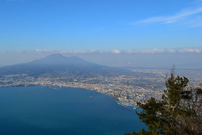 Aerial view of city by sea against sky