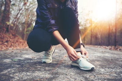 Low section of woman tying shoelace on footpath