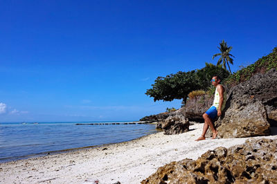 Rear view of woman standing on rocks at beach