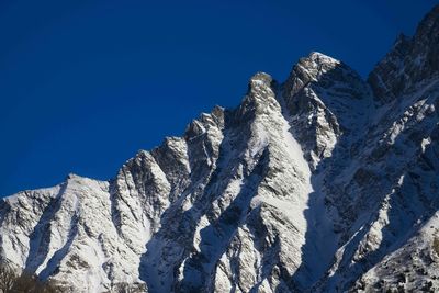 Low angle view of snowcapped mountain against blue sky