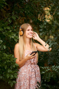 Smiling young woman standing against plants