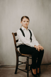 Girl sitting on chair against wall