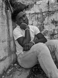 Portrait of boy sitting against wall