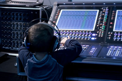 Rear view of boy using sound mixer in studio