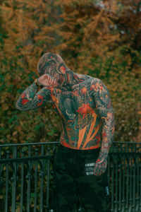 Rear view of man standing in forest, all covered tattoo body