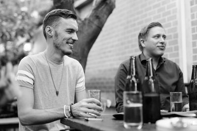 Smiling young man with drink sitting on table