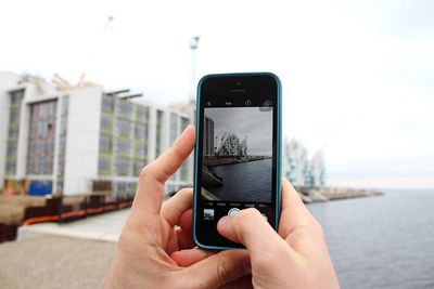 Cropped image of man photographing through smart phone