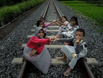 Portrait of smiling girl sitting on railroad track