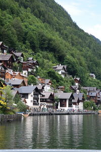 Buildings by lake against tree mountain in town