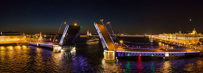 Illuminated bridge over river at night