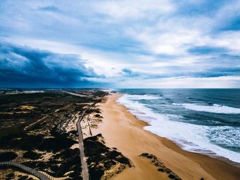 Scenic view of the beach with the waves reaching the sand and a dramatic sky touching the water 