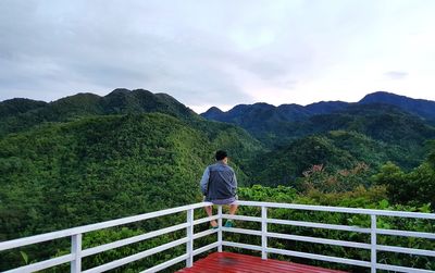 Rear view of woman looking at mountains against sky