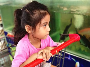 Close-up of cute girl sitting on shopping cart