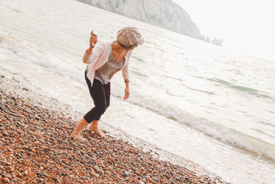 Woman throwing pebble in sea