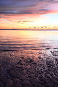 Scenic view of sea against dramatic sky during sunset