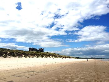 Scenic view of beach against cloudy sky