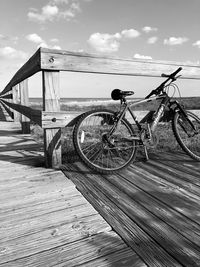 Bicycle parked by wooden post in city against sky