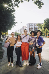 Full length portrait of smiling young lgbtqia friends standing on footpath