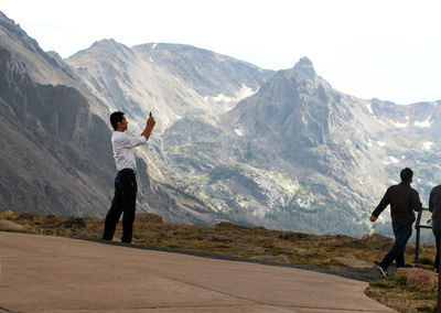 Young man photographing mountain against sky