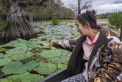 Side view of woman sitting by lake