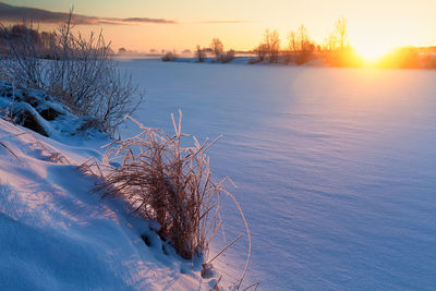 Frozen lake against sky during sunset