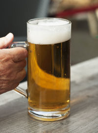 Close-up of hand holding beer glass on table