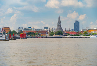 Buildings by river against sky in city