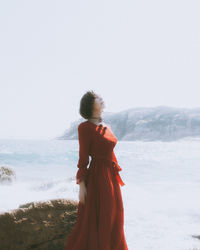 Young woman at beach against sky