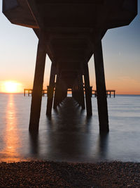 Pier over sea against sky during sunset